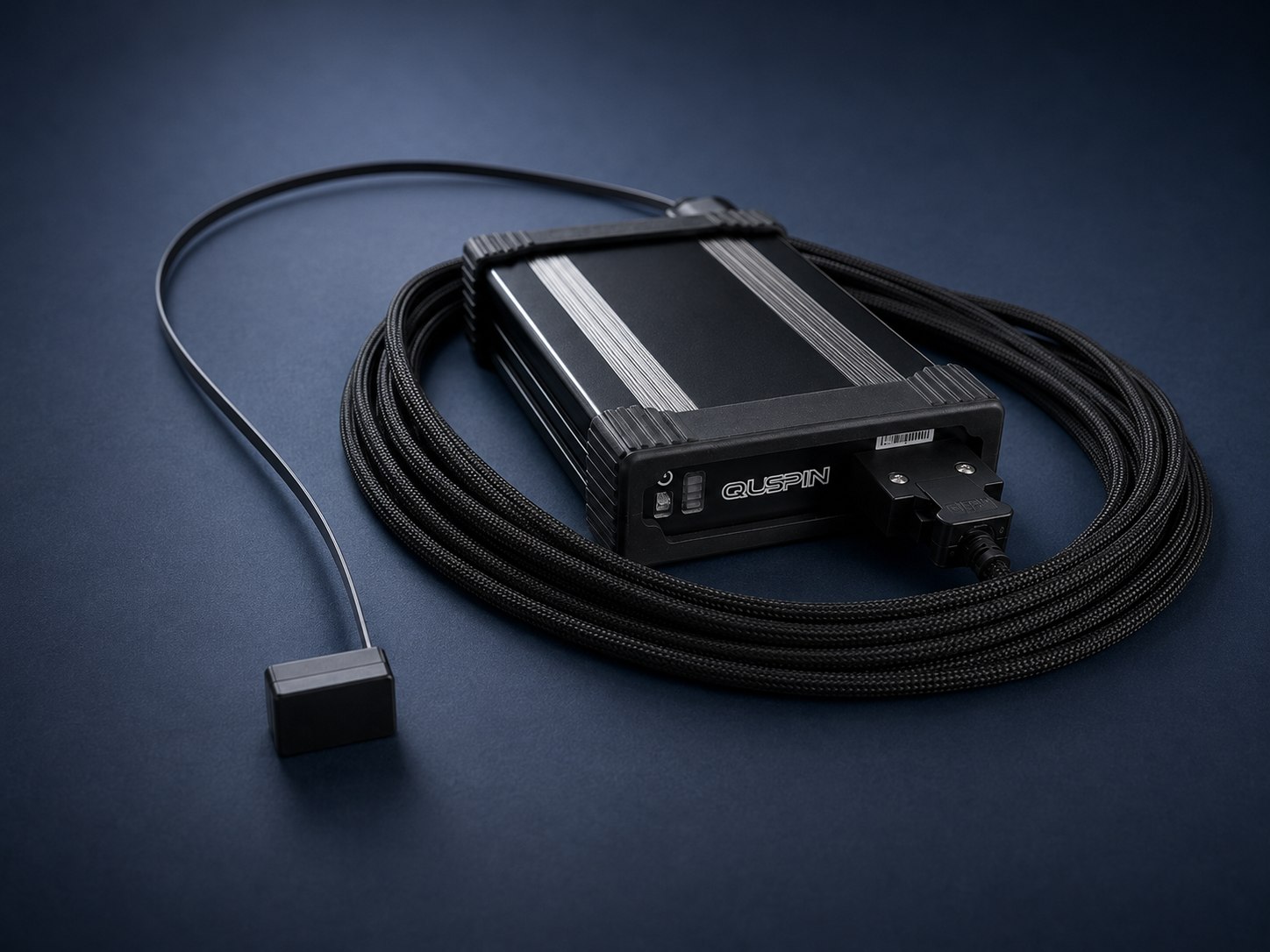 QZFM Gen-3 sensor head connected by its braided cable to the matched electronics module, on a white background