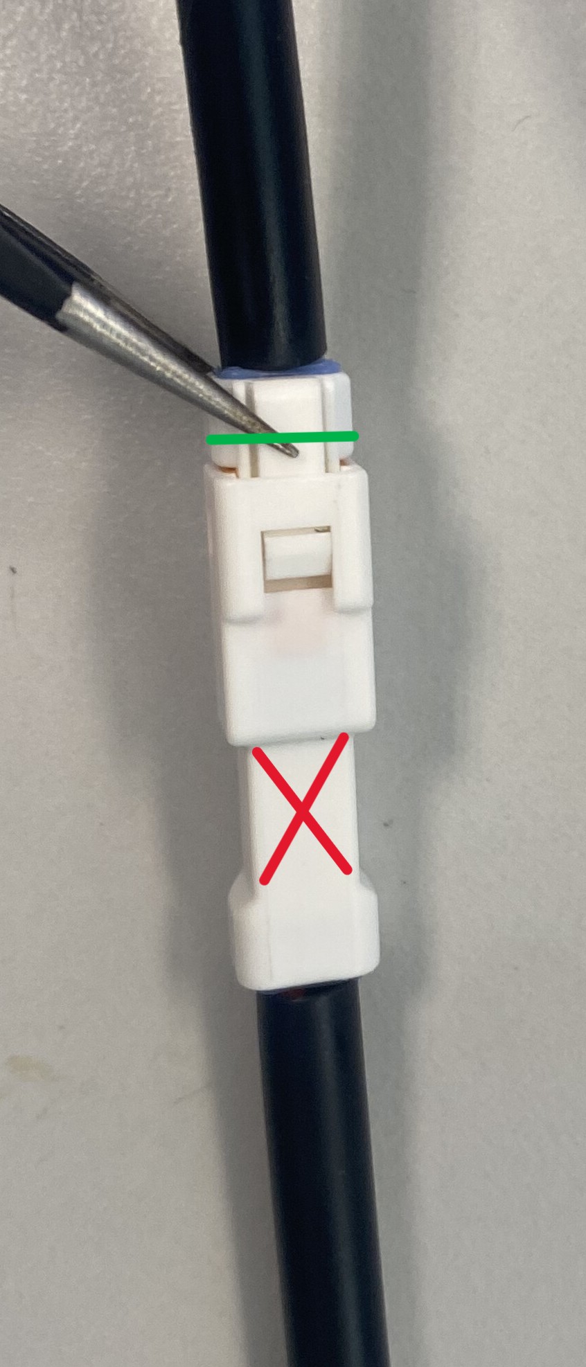 Releasing the locking tab with a screwdriver at the correct connector (green), not the battery connector (red)