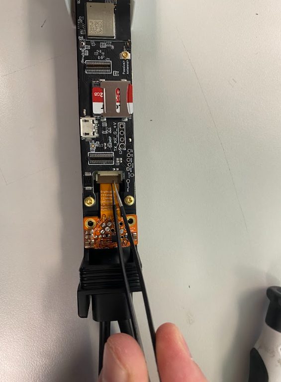 Hinged flex-cable connector being disconnected with tweezers
